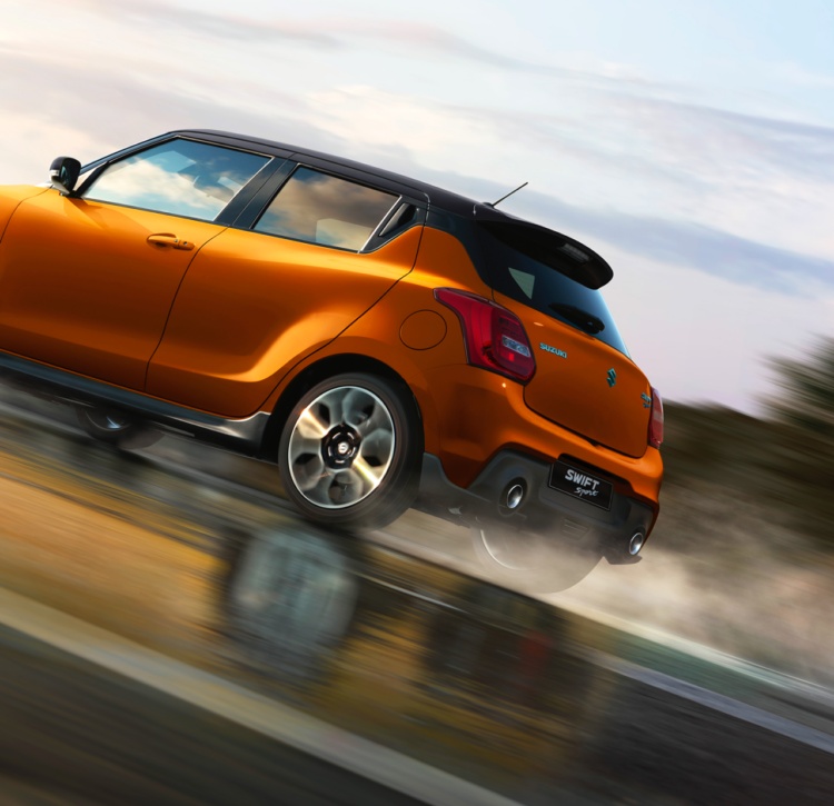 Two-tone Orange Swift Sport driving on wet road