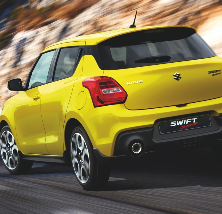 Yellow Swift Sport rear view on open road