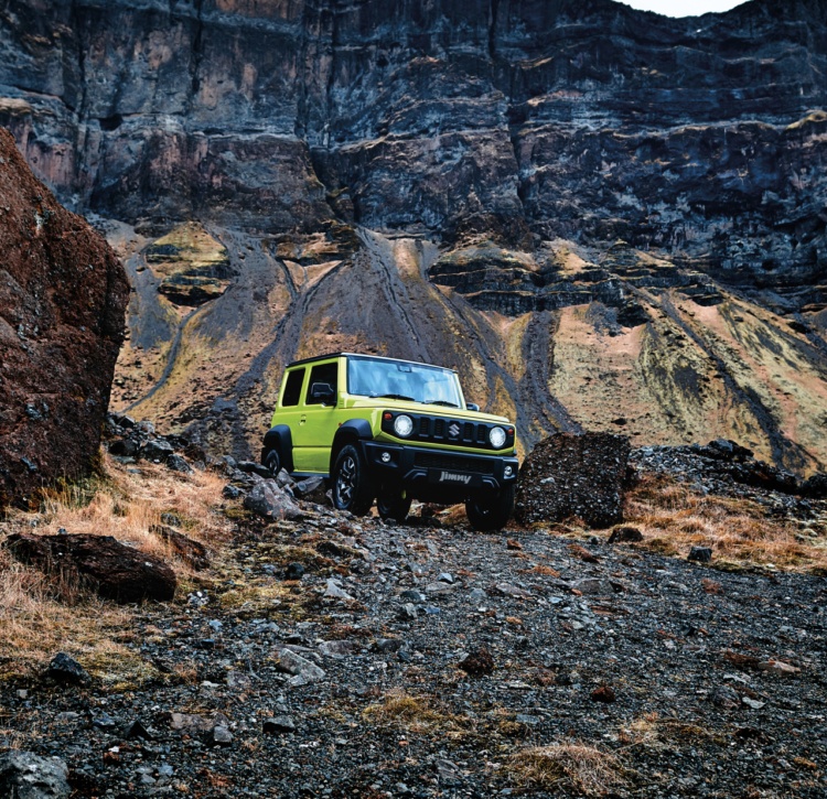 Green Jimny off road in rocks