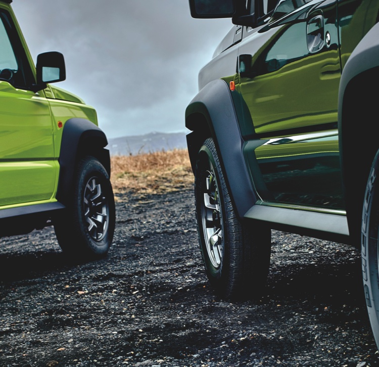 Green and black Jimny models parked side by side
